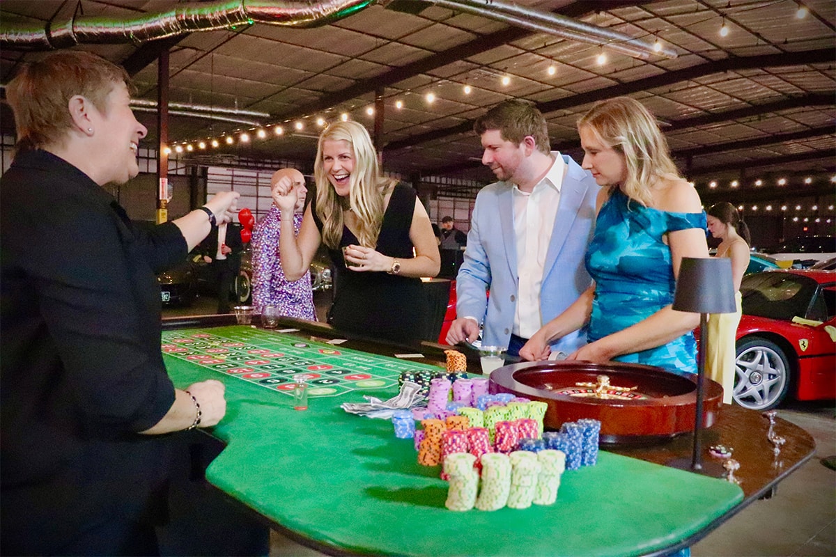 Guests celebrating a roulette win at an Austin Casino Party USA event with luxury cars in the background