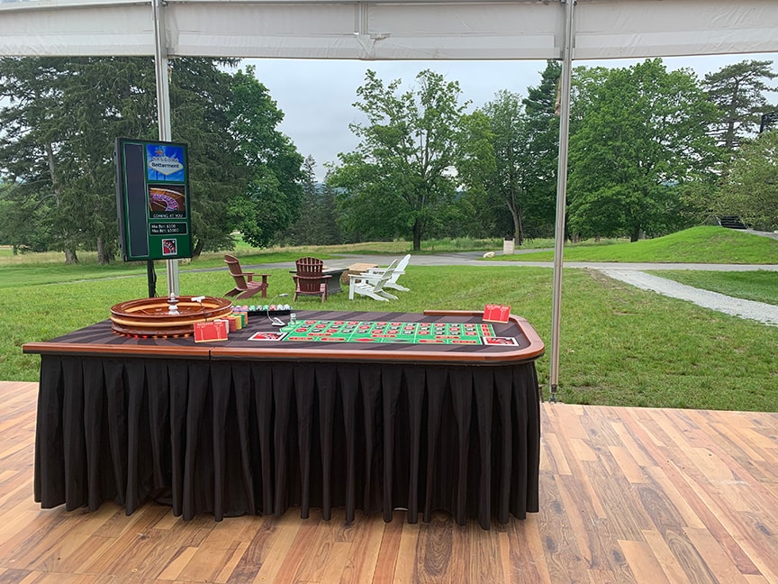 Outdoor roulette table set up under a tent at a Boston Casino Party USA event with scenic green landscape backdrop