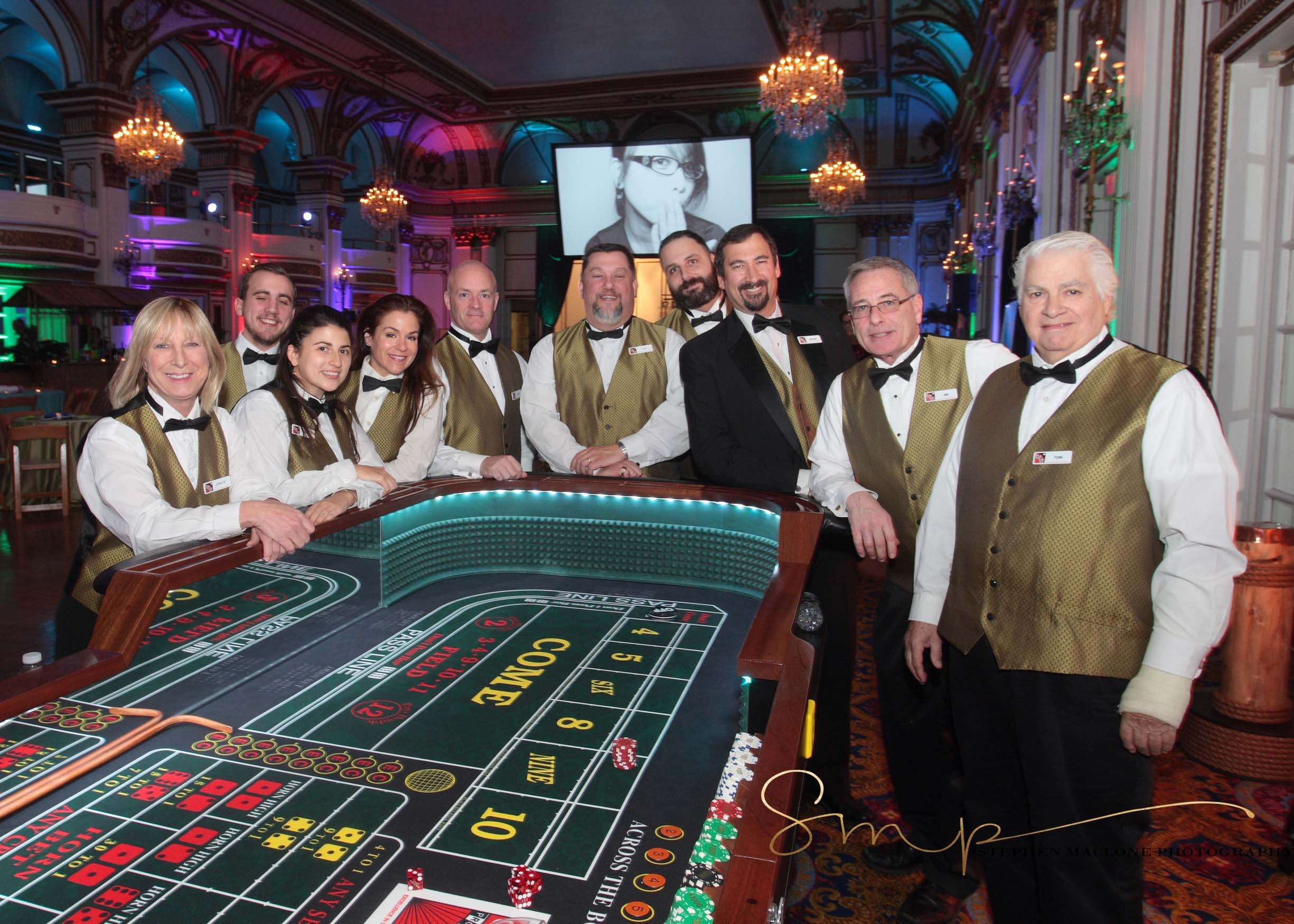 Casino Party USA dealer team posing around a craps table in an elegant ballroom at a Boston casino event