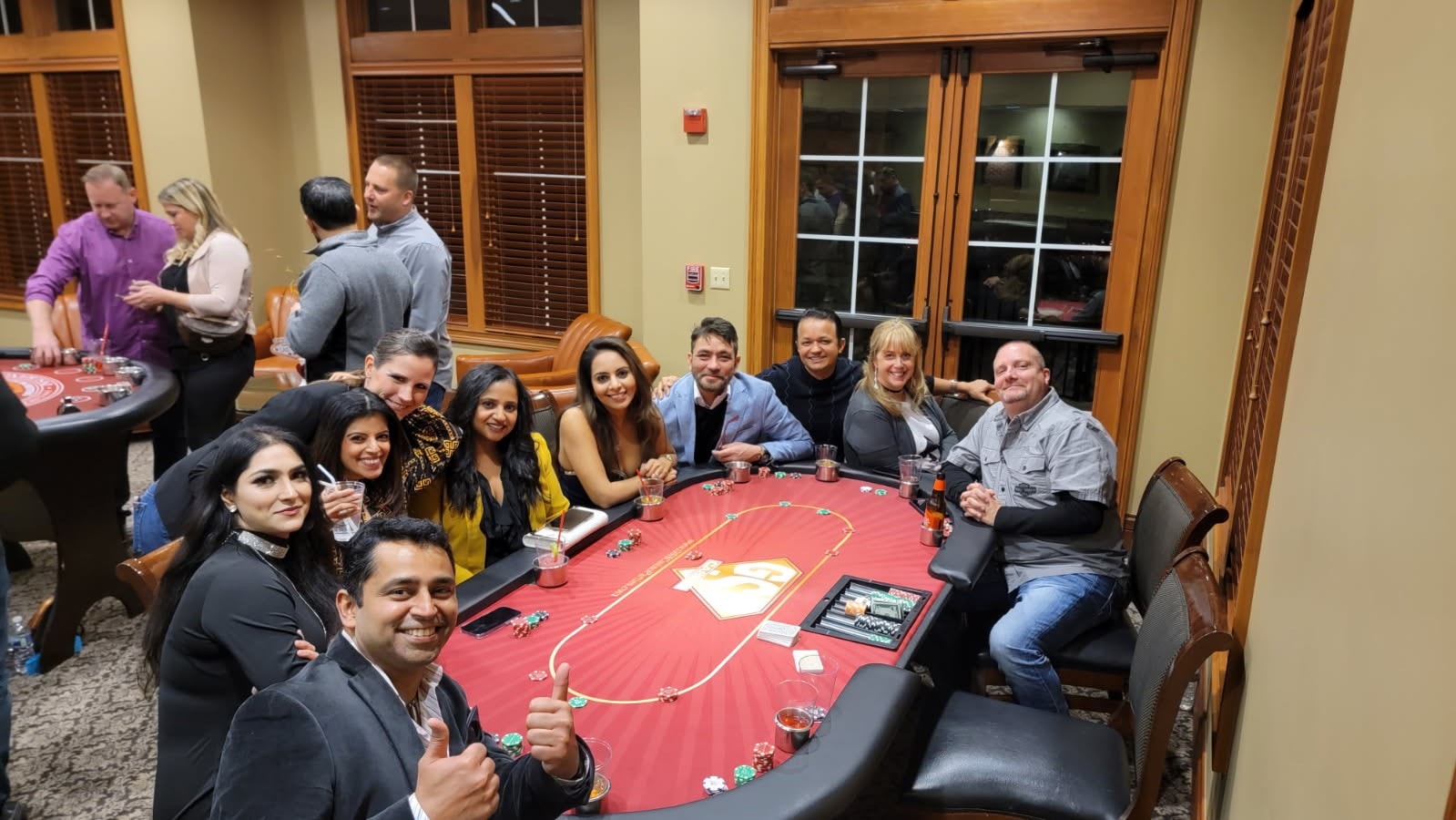 Full ballroom of guests playing casino table games with blue uplighting at a Casino Party USA event