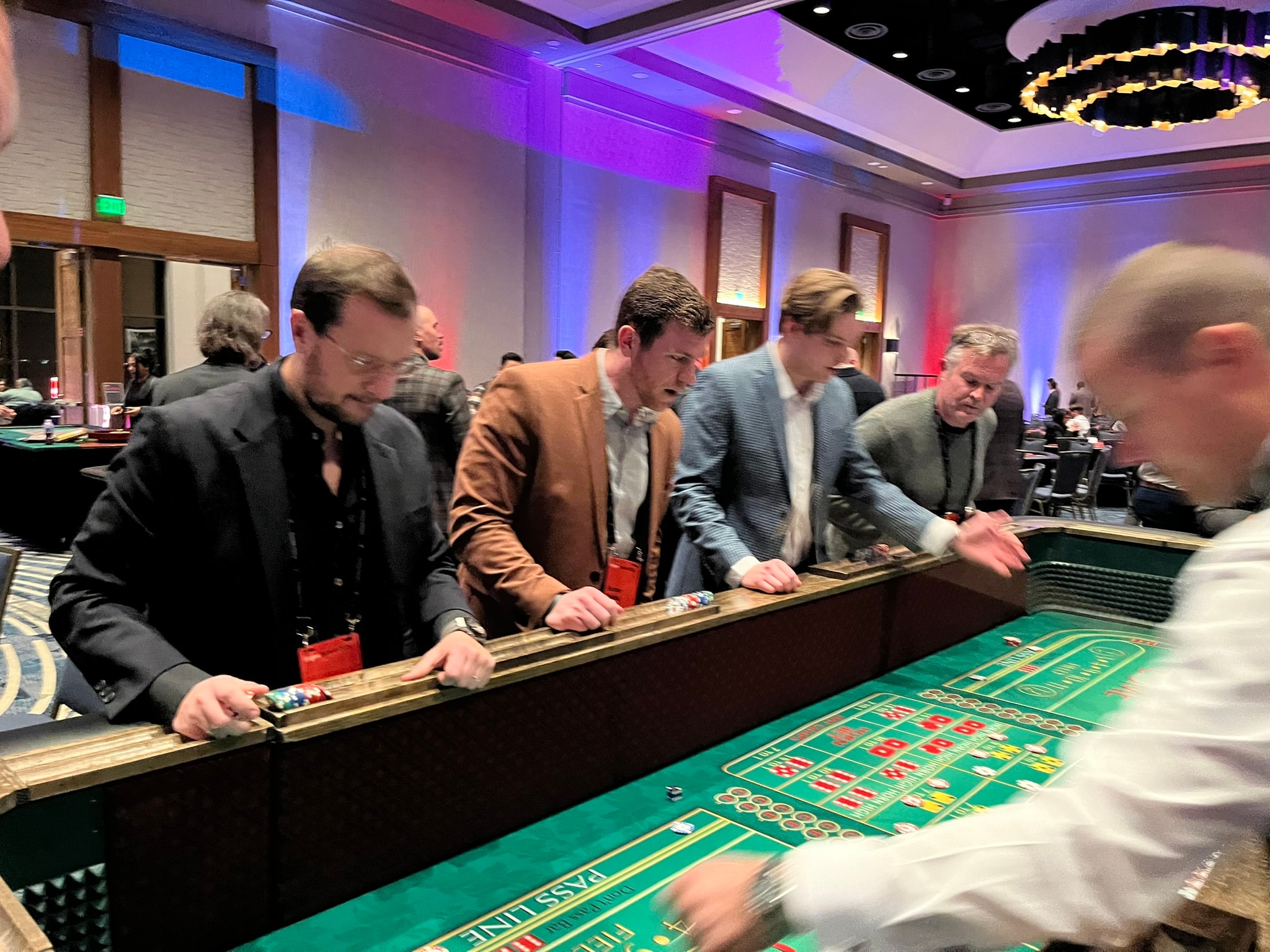 Guests leaning over a craps table with intense focus at a Denver Casino Party USA event