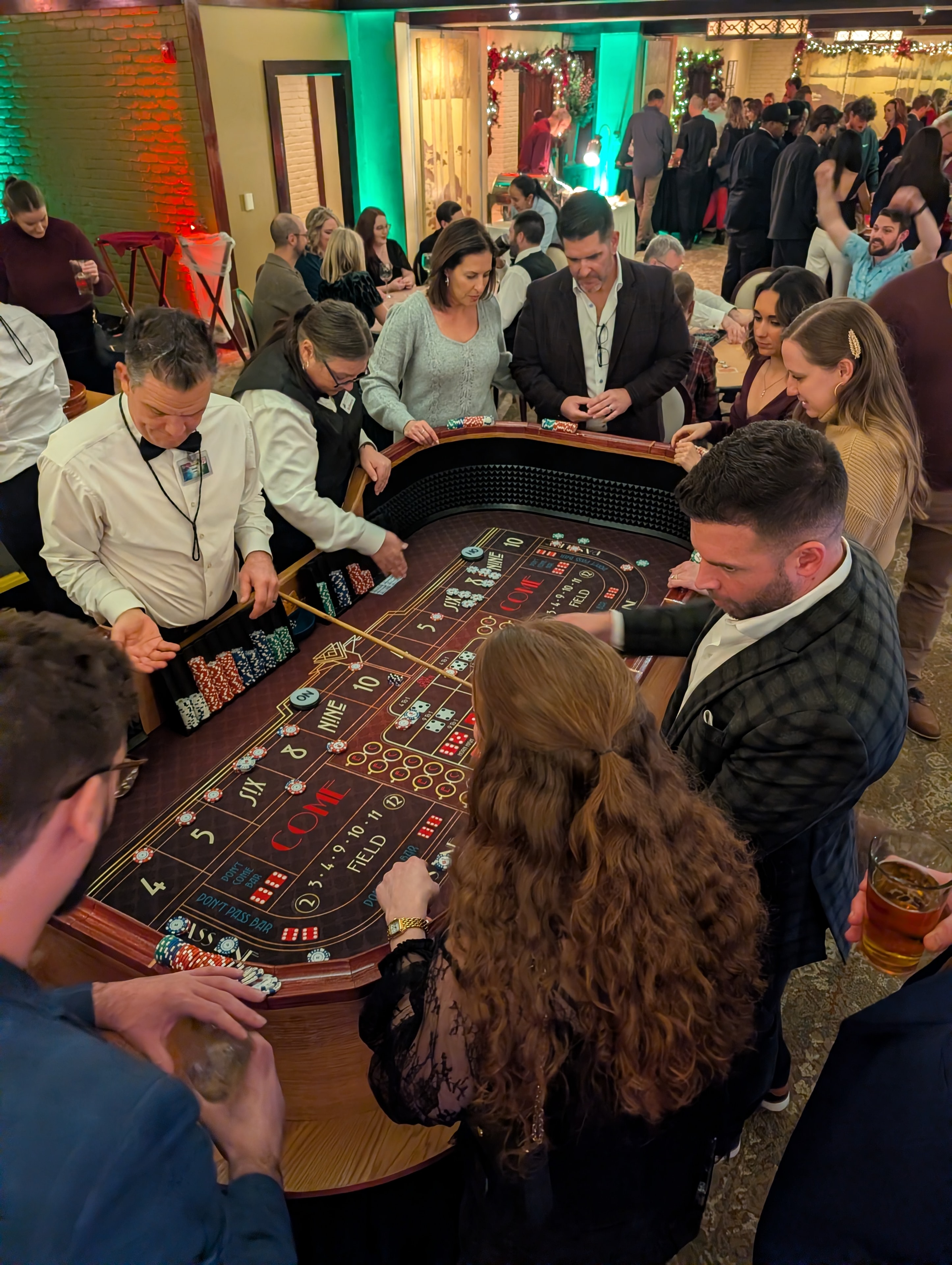 Packed craps table with guests and two dealers at a Casino Party USA Detroit holiday event
