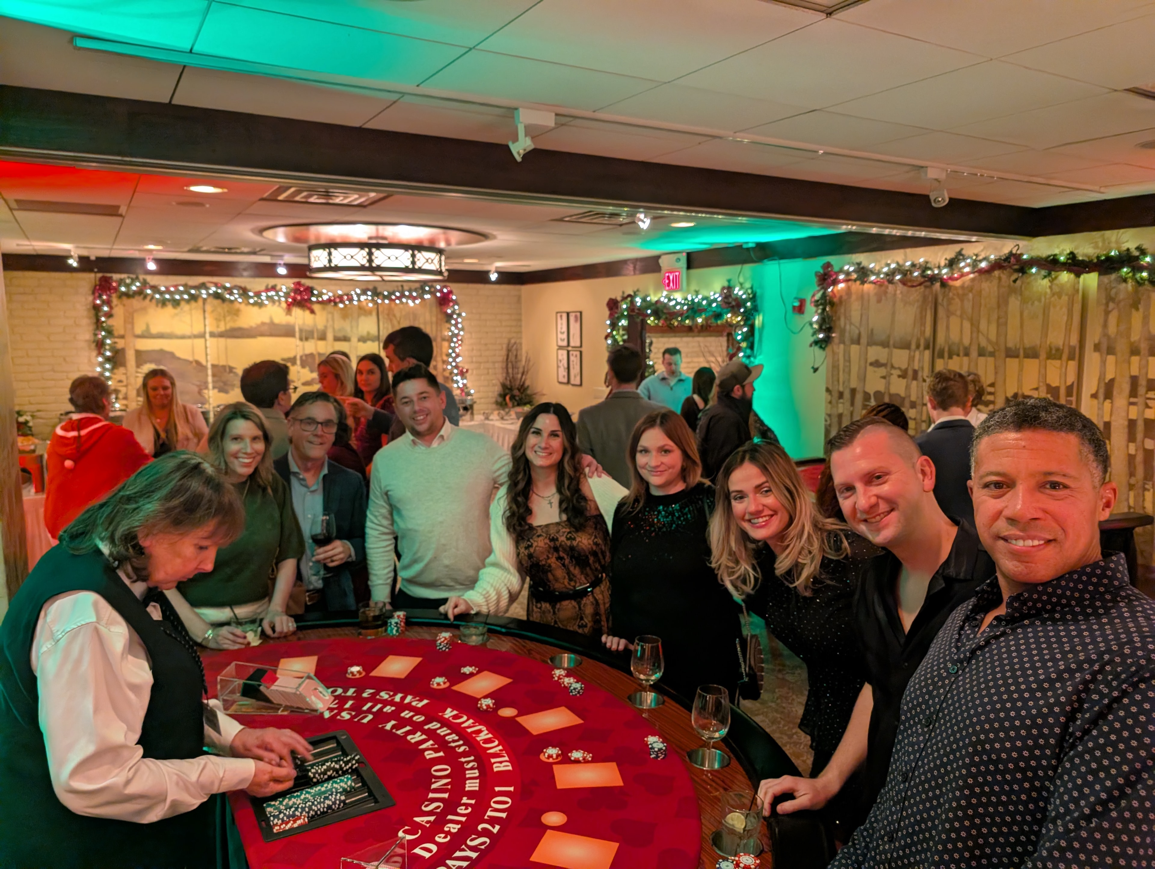 Large group of guests posing at a Casino Party USA blackjack table at a Detroit holiday event