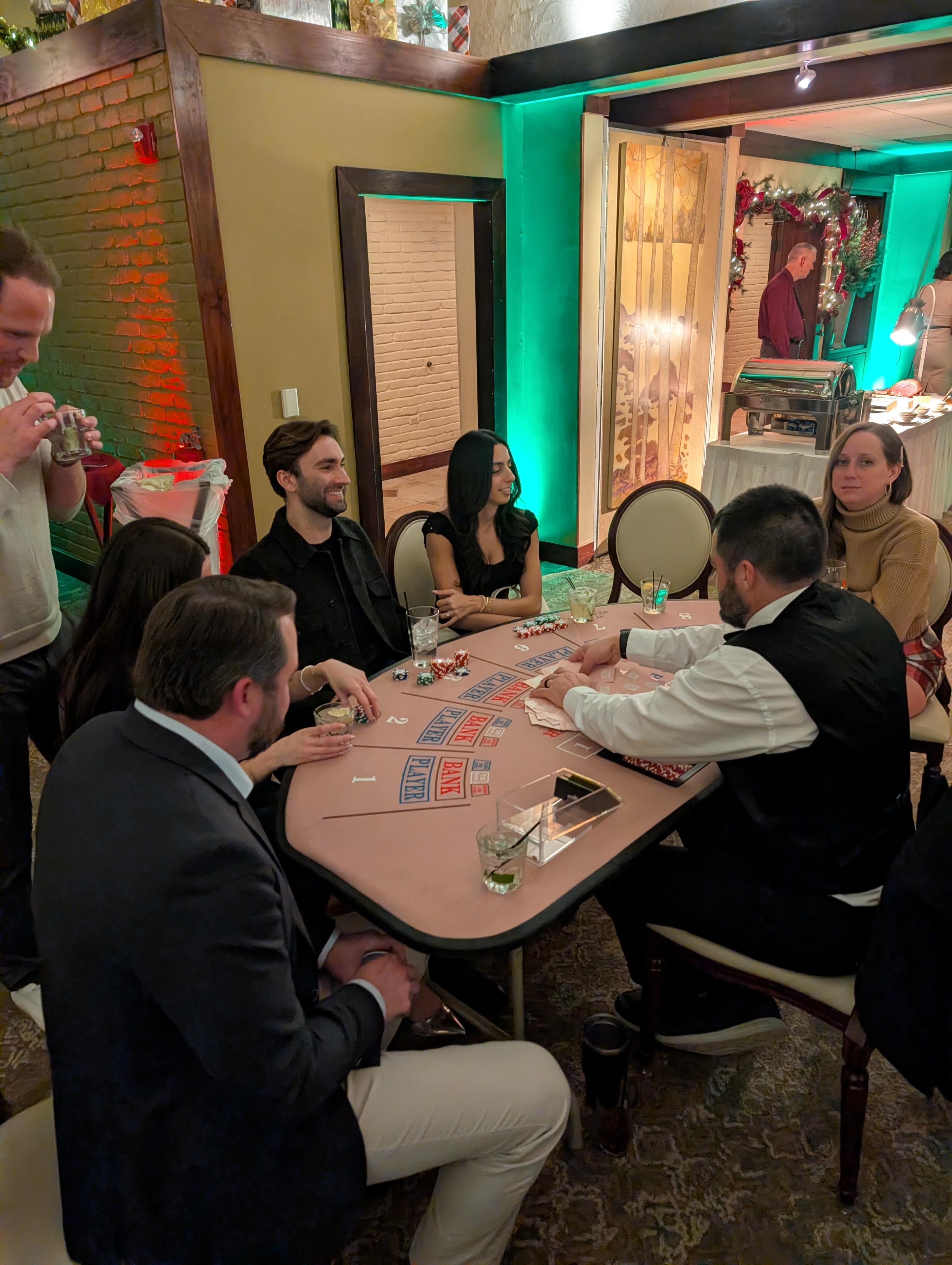 Guests playing baccarat at a Casino Party USA table with teal uplighting at a Detroit event
