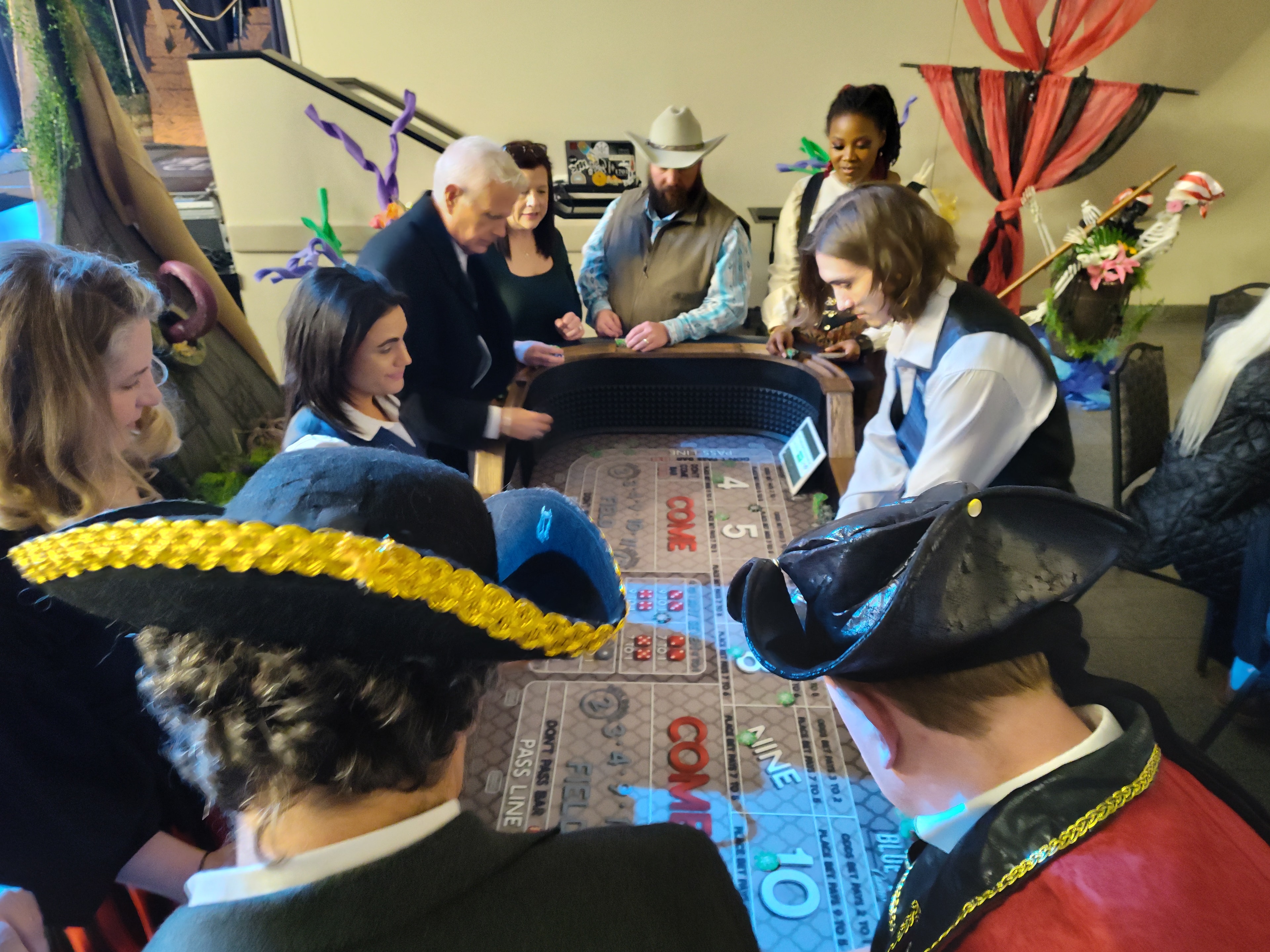 Guests in pirate hats crowded around a Blue Label craps table at a Houston casino party event