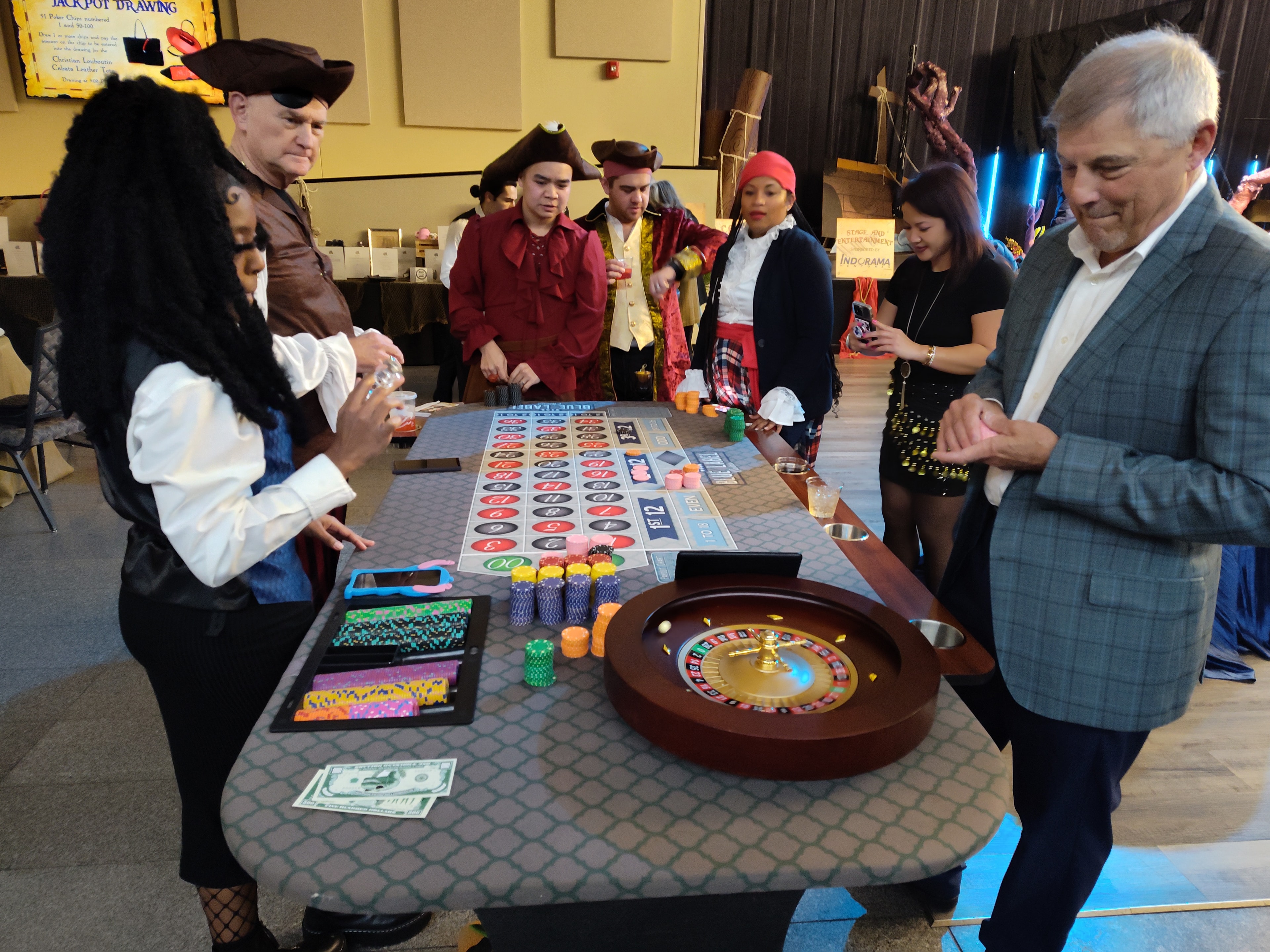 Guests in pirate costumes crowded around a roulette table at a Blue Label Casinos Houston event
