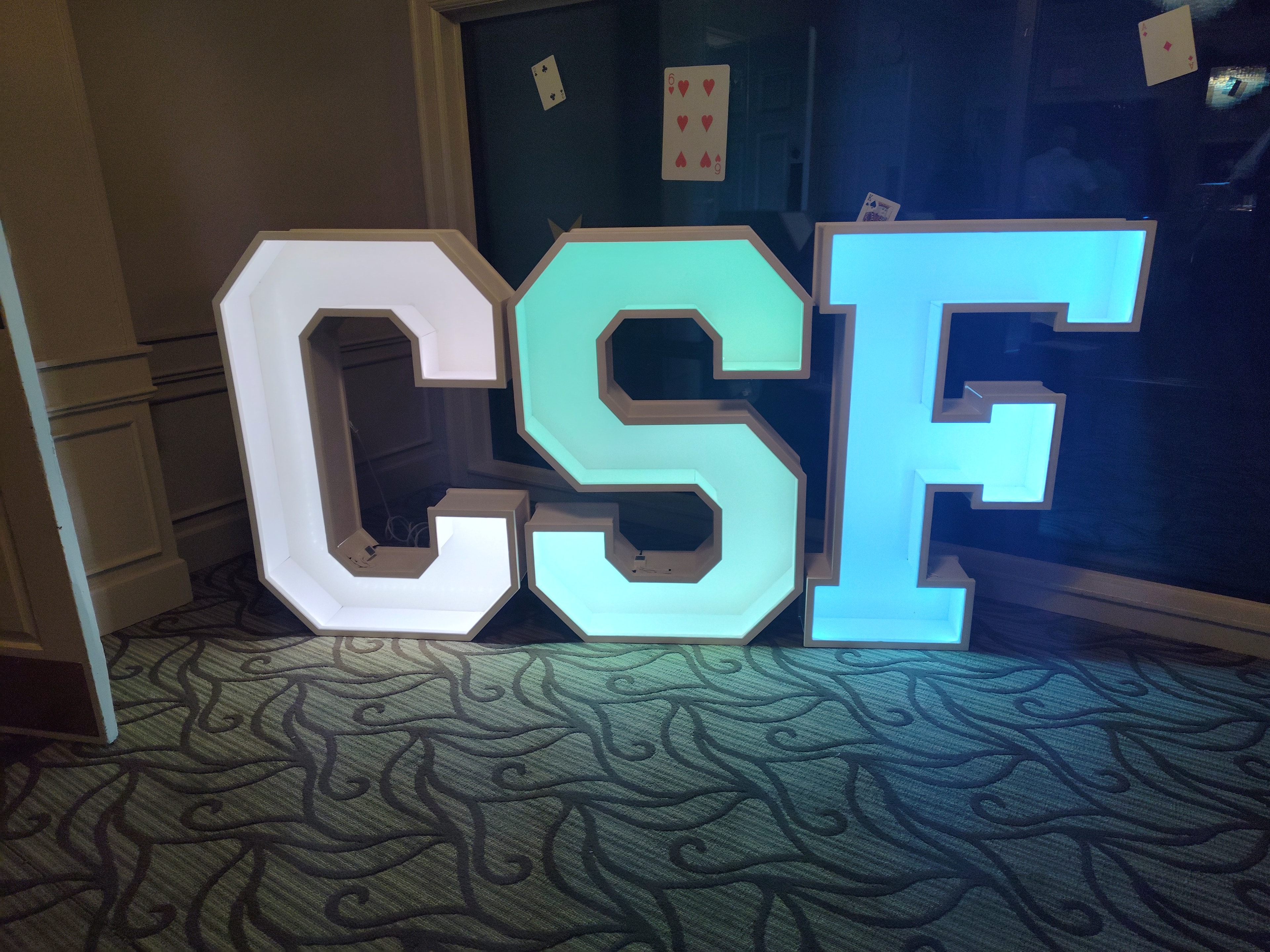 Color-changing LED marquee letters CSF in white, teal, and blue at casino night