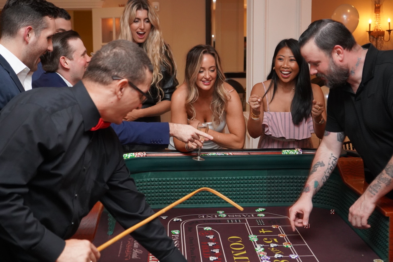 Excited guests cheering at a craps table during a New Jersey casino theme party