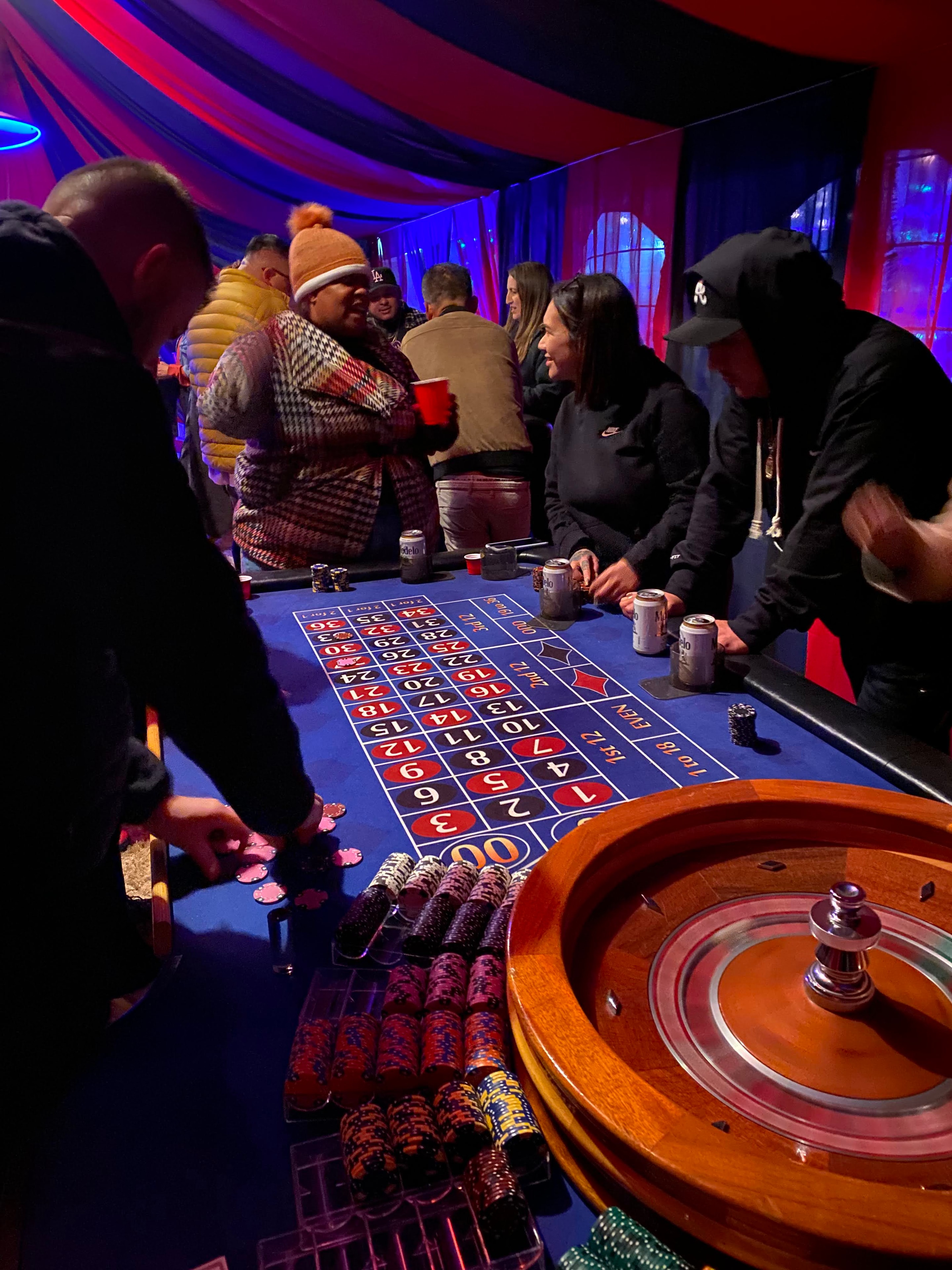 Guests at a roulette table under vibrant neon lighting at a Lancaster holiday casino party