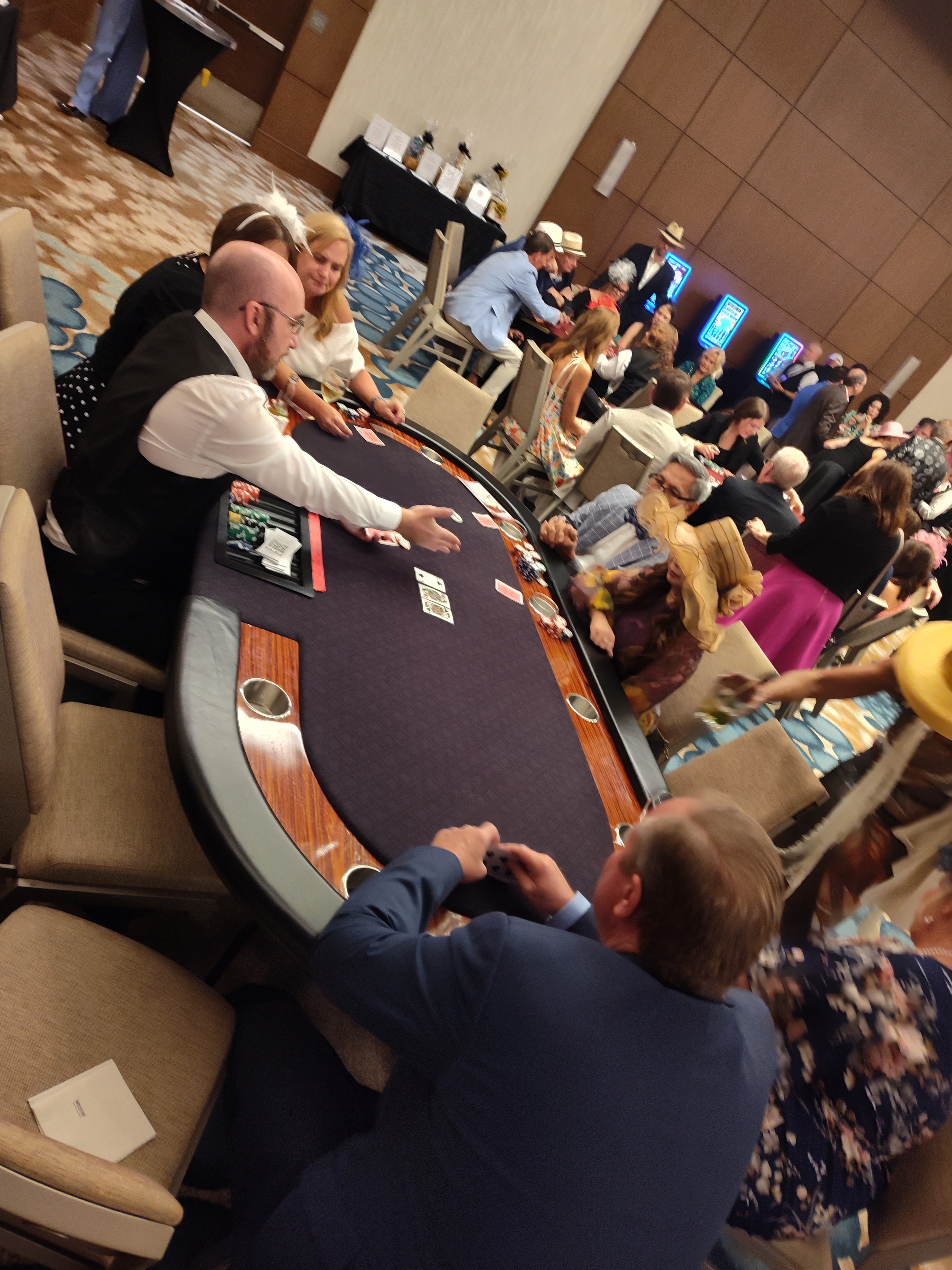 Dealer dealing cards at a poker table with a full crowd behind at an Orlando Casino Party USA event
