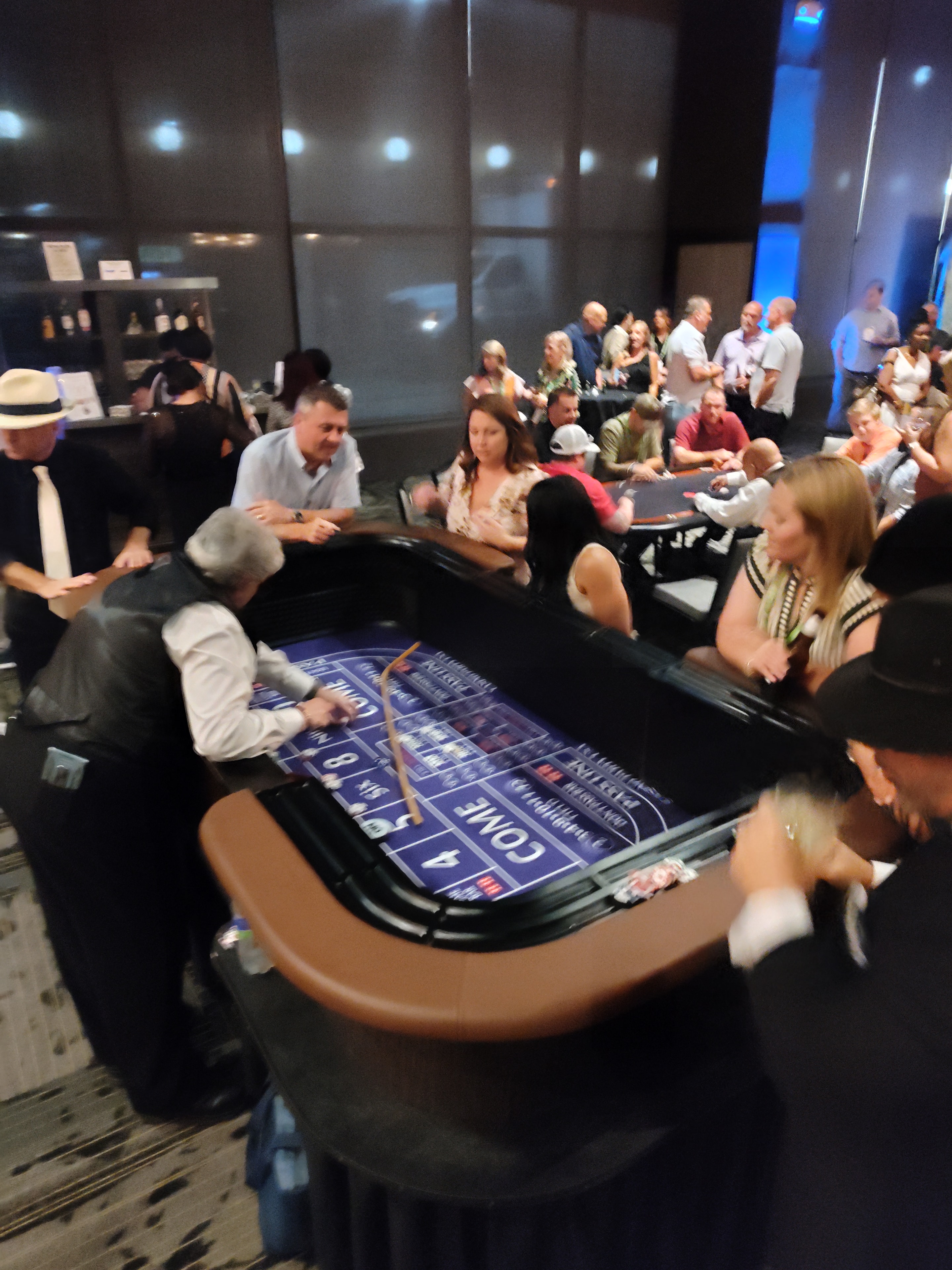 Large crowd packed around a Casino Party USA blue craps table at a Savannah corporate event