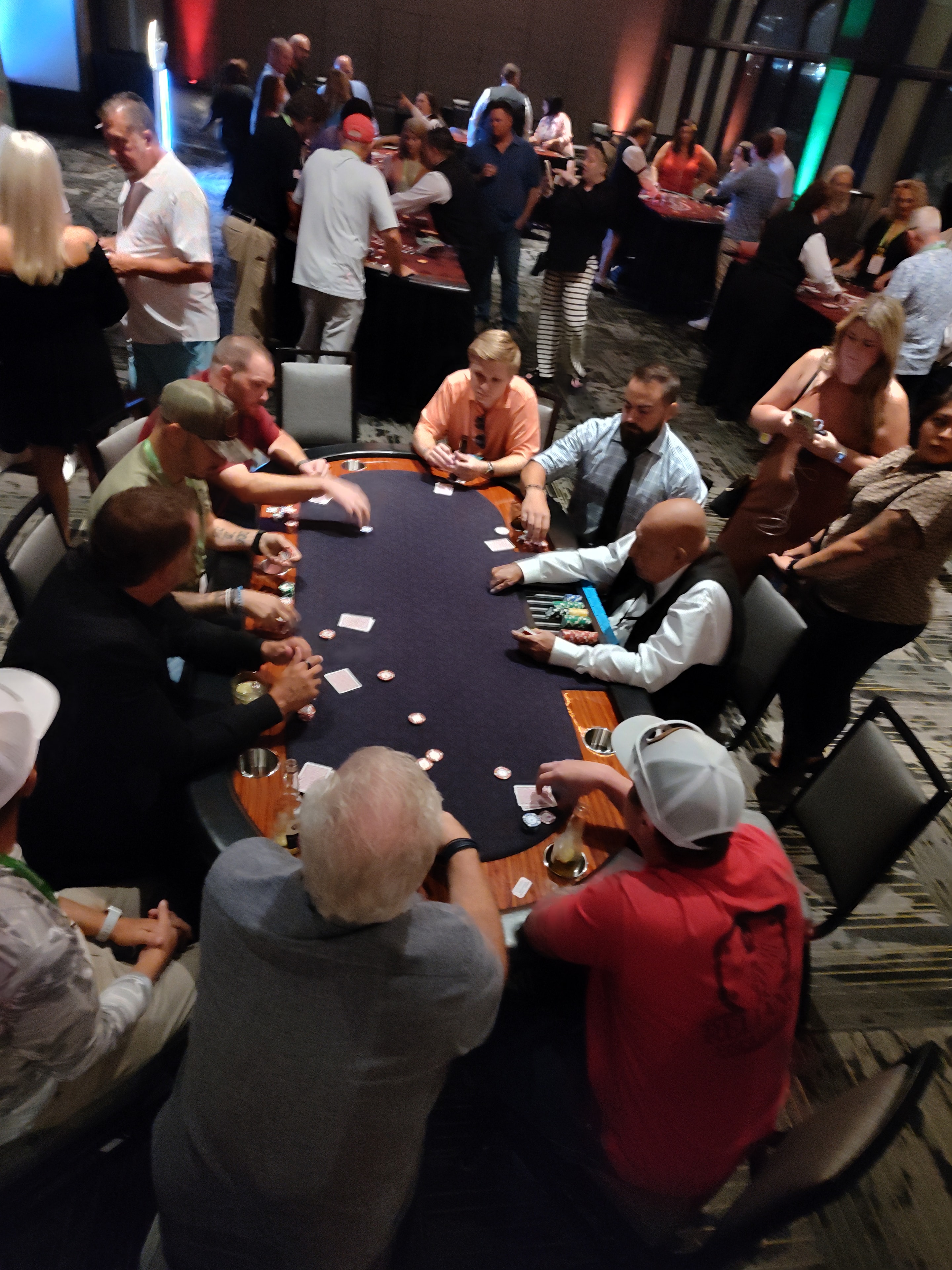 Overhead view of a full Casino Party USA poker table with a large crowd of guests at a Savannah event