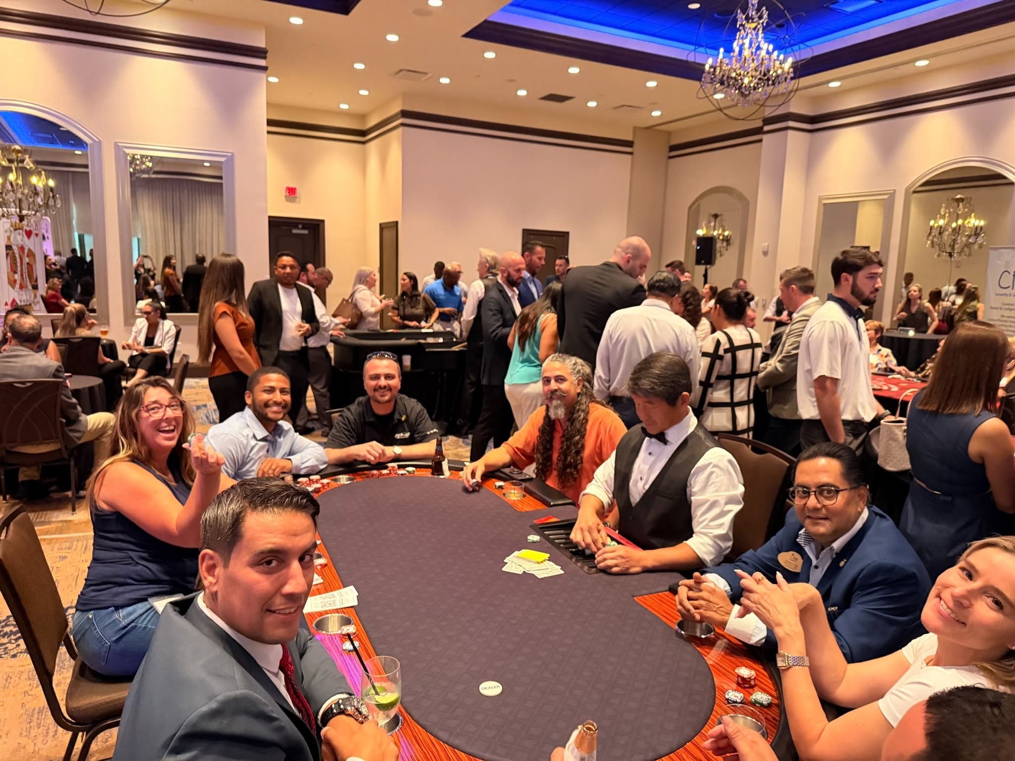 Guests smiling at a poker table in a large ballroom at a Tampa Casino Party USA event