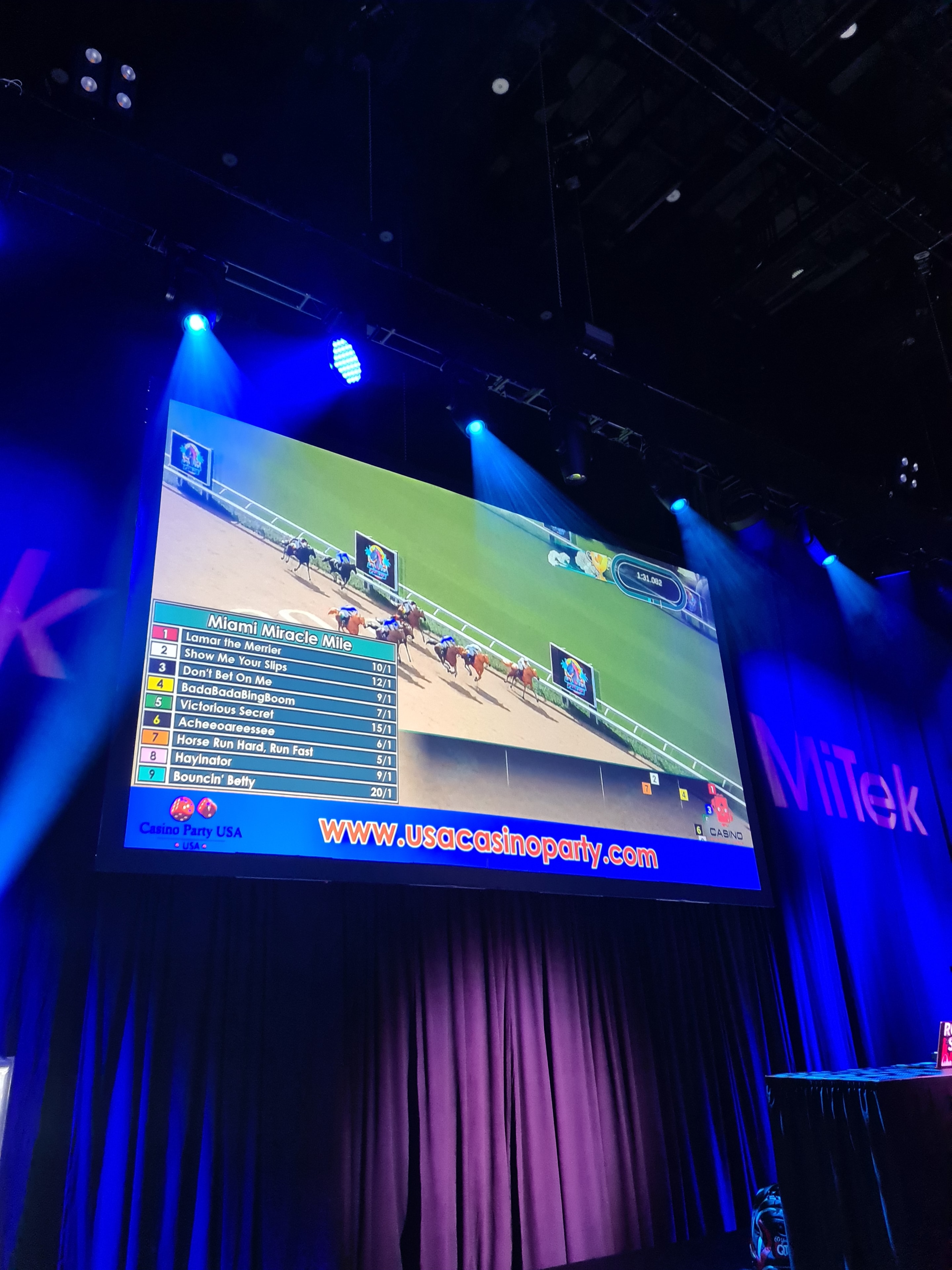 Casino Party USA video horse racing displayed on a large screen with stage lighting at a live event