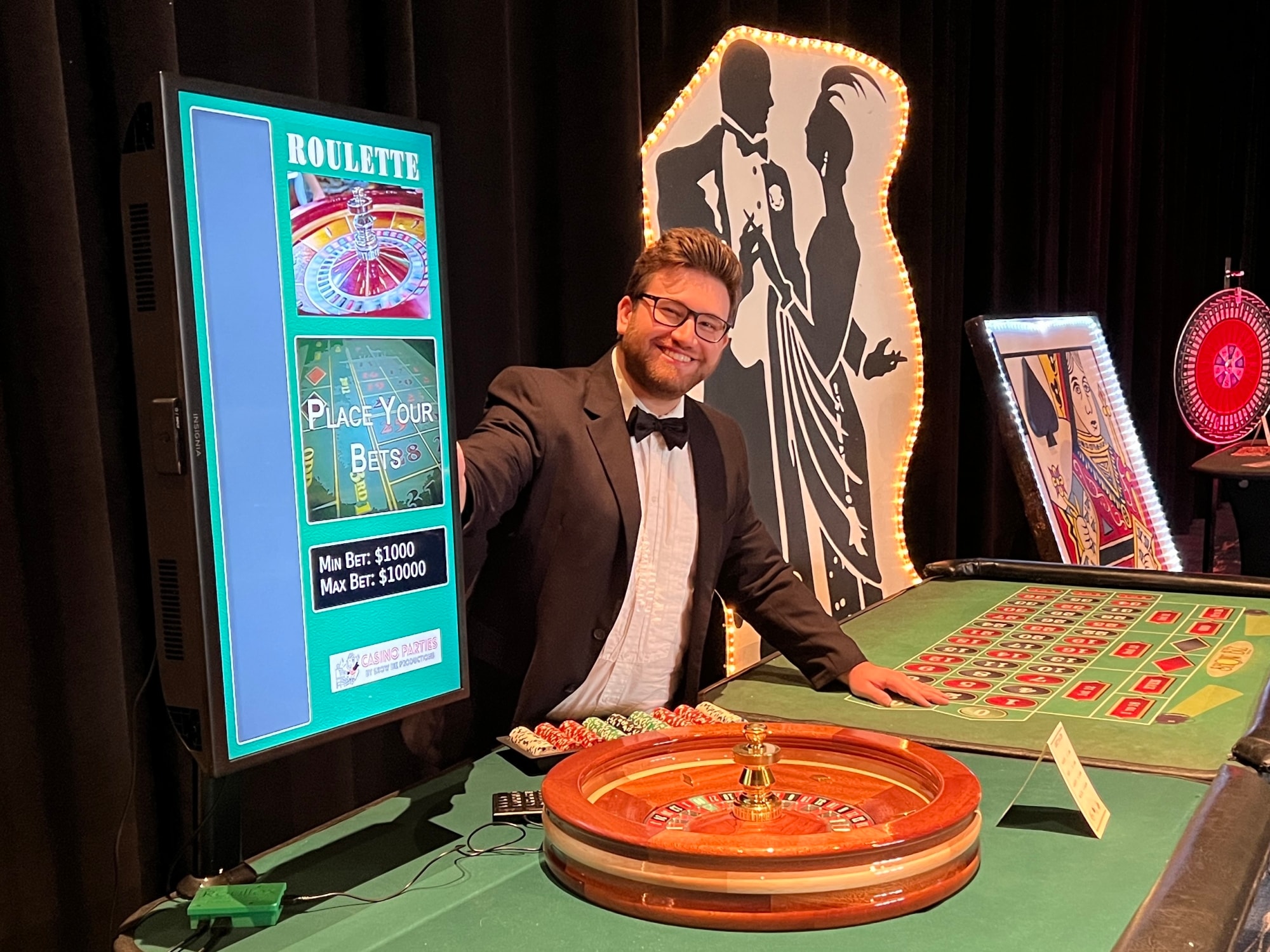 Smiling dealer posing at a roulette table with casino décor at a Washington DC Casino Party USA event