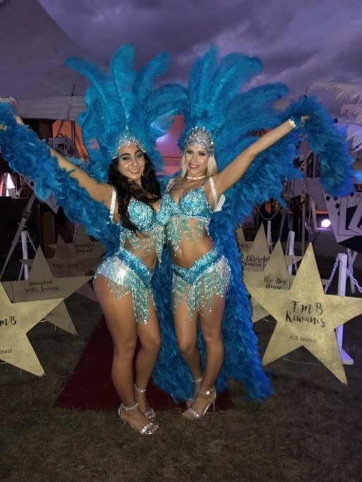 Two showgirls in blue feathered costumes posing at a Washington DC Casino Party USA outdoor event